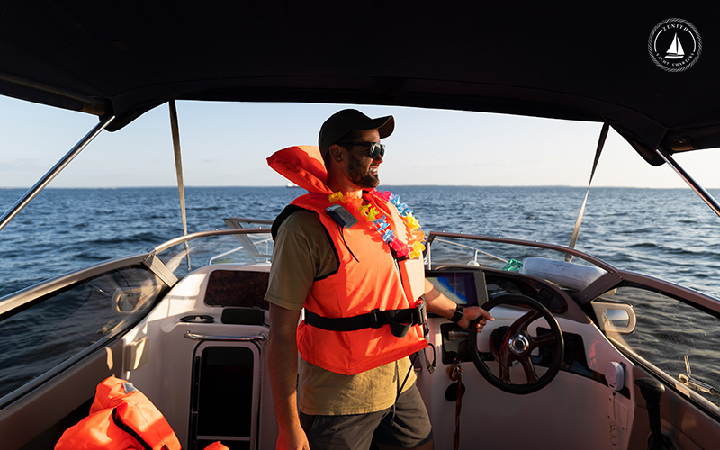 Man with a life jacket on a yacht sails across serene waters